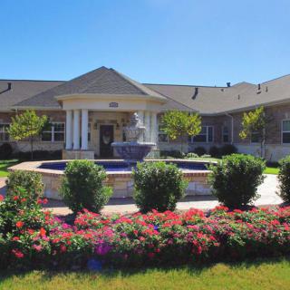 A well-maintained building front with a garden and fountain.