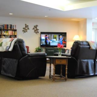 A cozy living room with recliners, a TV, bookshelves, and decorative elements.