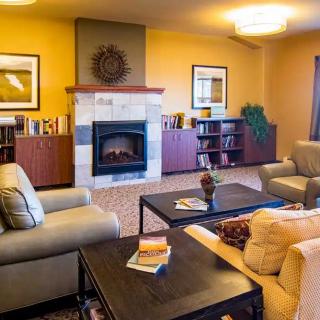 A cozy living room featuring comfortable sofas, a central fireplace, and bookshelves filled with books.