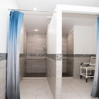 A modern bathroom featuring individual shower stalls with curtains, tiled walls, and a clean aesthetic.