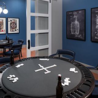 A stylish game room featuring a domino table, blue walls, and framed posters.