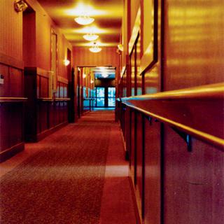 A dimly lit hallway with carpet flooring and wooden panels.
