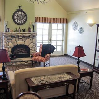 A cozy living room with a stone fireplace, sofa, chairs, and decorative elements.