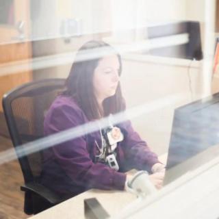 A woman working on a computer at her desk in an office.