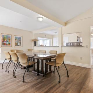 A modern dining room with a wooden table, beige chairs, and artwork on the walls.