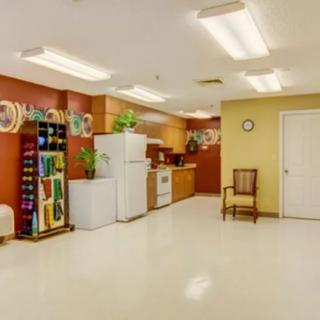 A spacious kitchen area with a refrigerator, shelves, and seating.