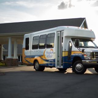 A shuttle bus parked in front of a building on a sunny day.