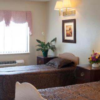 A cozy hotel room with twin beds and simple decor.
