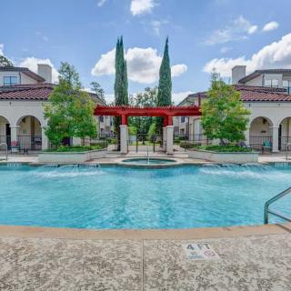 A beautifully designed outdoor pool area with surrounding architecture and trees.