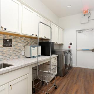 A modern laundry room with white cabinets, a washer and dryer, and wooden flooring.