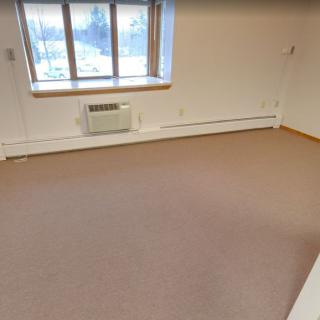 An unfurnished room with a window and carpeted floor.