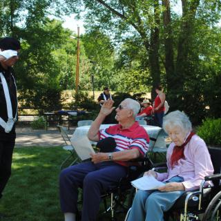 A group of elderly people enjoying time together outdoors in a garden setting.