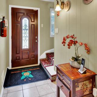A cozy entryway featuring a wooden door, decorative doormat, and a wooden side table with a flower vase.