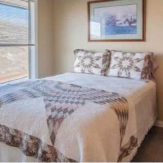 A cozy bedroom with a patterned quilt and artwork above the bed.
