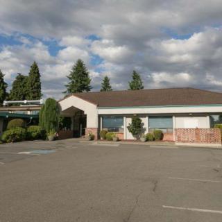 A standalone building with a parking lot under a cloudy sky.