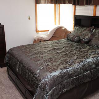 A cozy bedroom with a well-made bed and large windows.