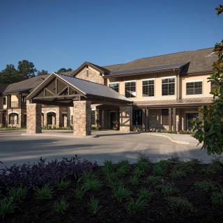 A modern building with a covered entrance and landscaped surroundings.