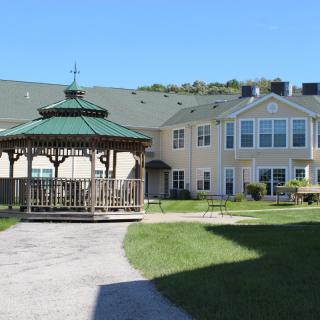 A sunny view of a residential building with a gazebo and green lawn.