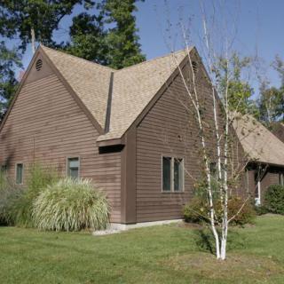 A wooden house surrounded by a landscaped yard with trees and grass.
