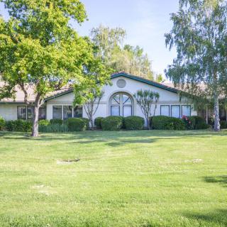 A picturesque residential house surrounded by a lush green lawn and tall trees.