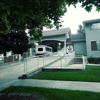A view of a residential building featuring a wheelchair accessible ramp and well-maintained landscaping.