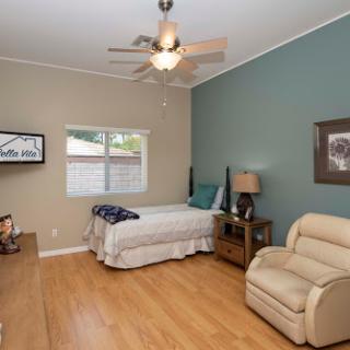 A cozy and well-lit bedroom featuring a single bed, a comfortable chair, and modern decor.