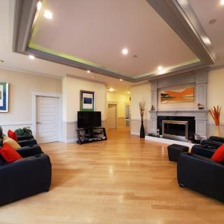 A spacious modern living room with hardwood flooring, featuring comfortable sofas, a fireplace, and a television, accented by contemporary artwork.