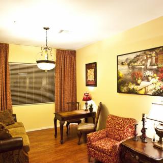 A cozy living room with warm lighting and classic decor, featuring a sofa, table, and chairs.