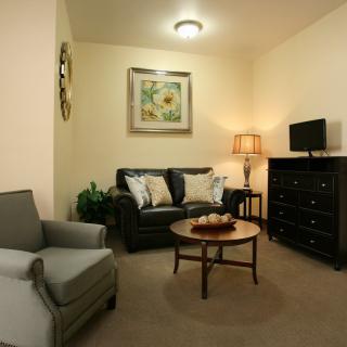 A cozy living room with a sofa, armchair, and a coffee table under soft lighting.