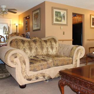 A cozy living room featuring a patterned sofa and a wooden coffee table, adorned with artwork on the walls.