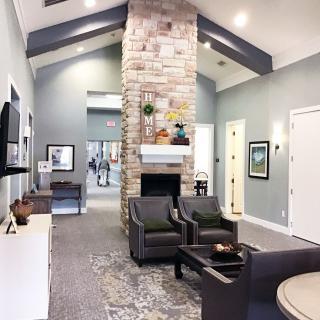 A contemporary living room with a central stone fireplace and comfortable seating.