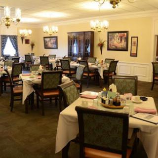 A beautifully arranged dining room with tables set for a meal, featuring elegant decor and warm lighting.