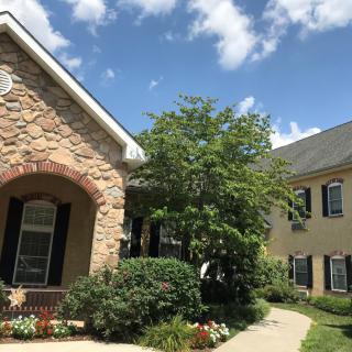 A beautiful residential house with a well-maintained garden and a clear blue sky.