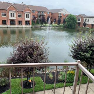 View from a balcony overlooking a small lake with a fountain and surrounding apartments.