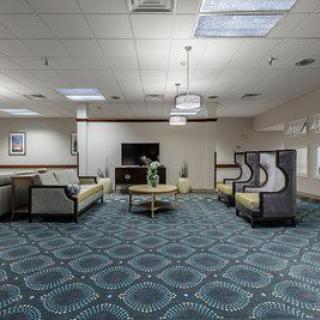 A spacious waiting room with modern furnishings and a patterned carpet.