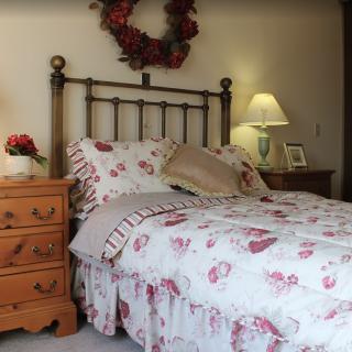 A cozy bedroom with floral bedding and a lamp on the nightstand.