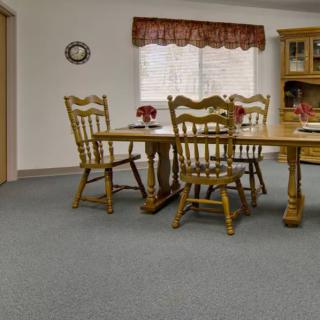 A cozy dining room with wooden furniture and a carpeted floor.