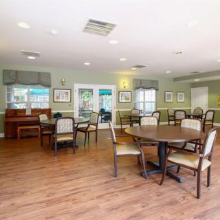 A spacious dining room with several tables and chairs, featuring wooden flooring and decorated walls.
