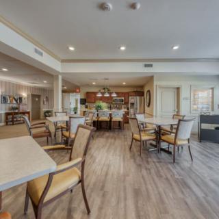 A spacious and well-lit dining area with tables and chairs on hardwood flooring.