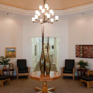 A well-decorated lobby with a central table featuring tall vases, surrounded by chairs and adorned with artwork on the walls.