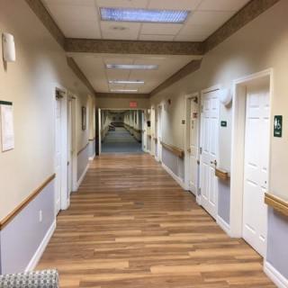 A long indoor corridor with doors on both sides and wooden flooring.