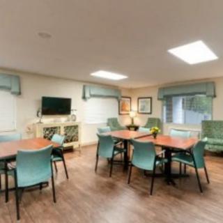 A well-lit meeting room with tables, chairs, and a television.