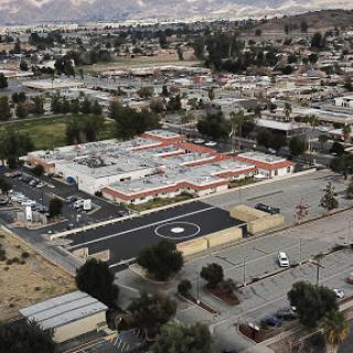 Aerial view of a commercial sector surrounded by nature, featuring rooftops and a parking area.