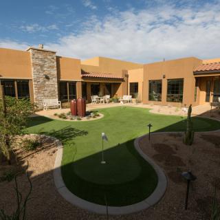 A modern desert home with a central courtyard featuring a manicured lawn and landscape.