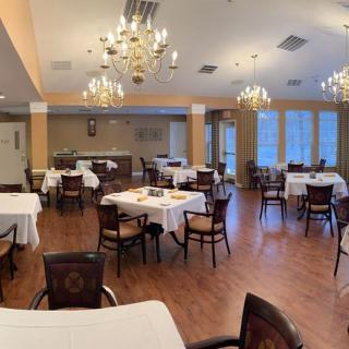 An elegant, empty dining room with neatly arranged tables and decorative chandeliers.