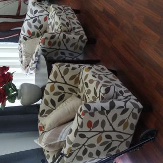 A cozy living room setup with floral patterned armchairs on a wooden floor.