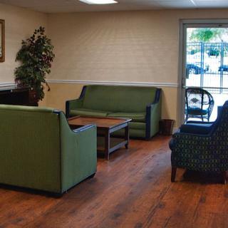 A cozy waiting room with green furniture and wood flooring.