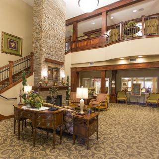 A spacious and elegantly designed lobby area featuring comfortable seating, a stone fireplace, and soft lighting.