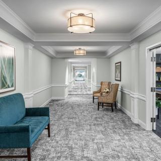 A modern hallway featuring seating areas, elegant lighting fixtures, and decorative artwork.