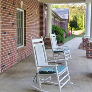 A peaceful porch with white rocking chairs and brick walls, perfect for relaxation.